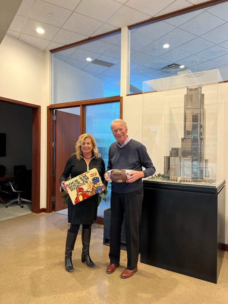 woman on the left and man on the right holding gifts for donation to Toys for Tots.